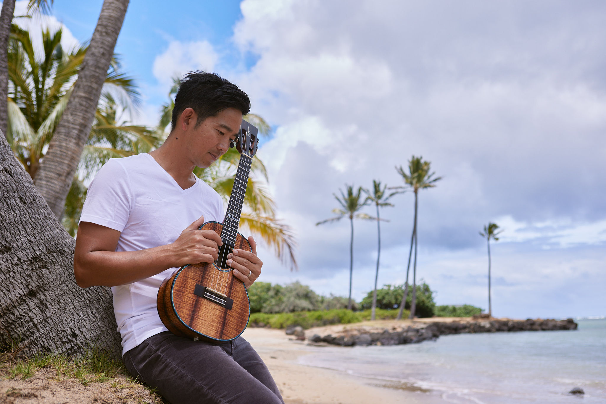 Man on a beach holding a ukelee