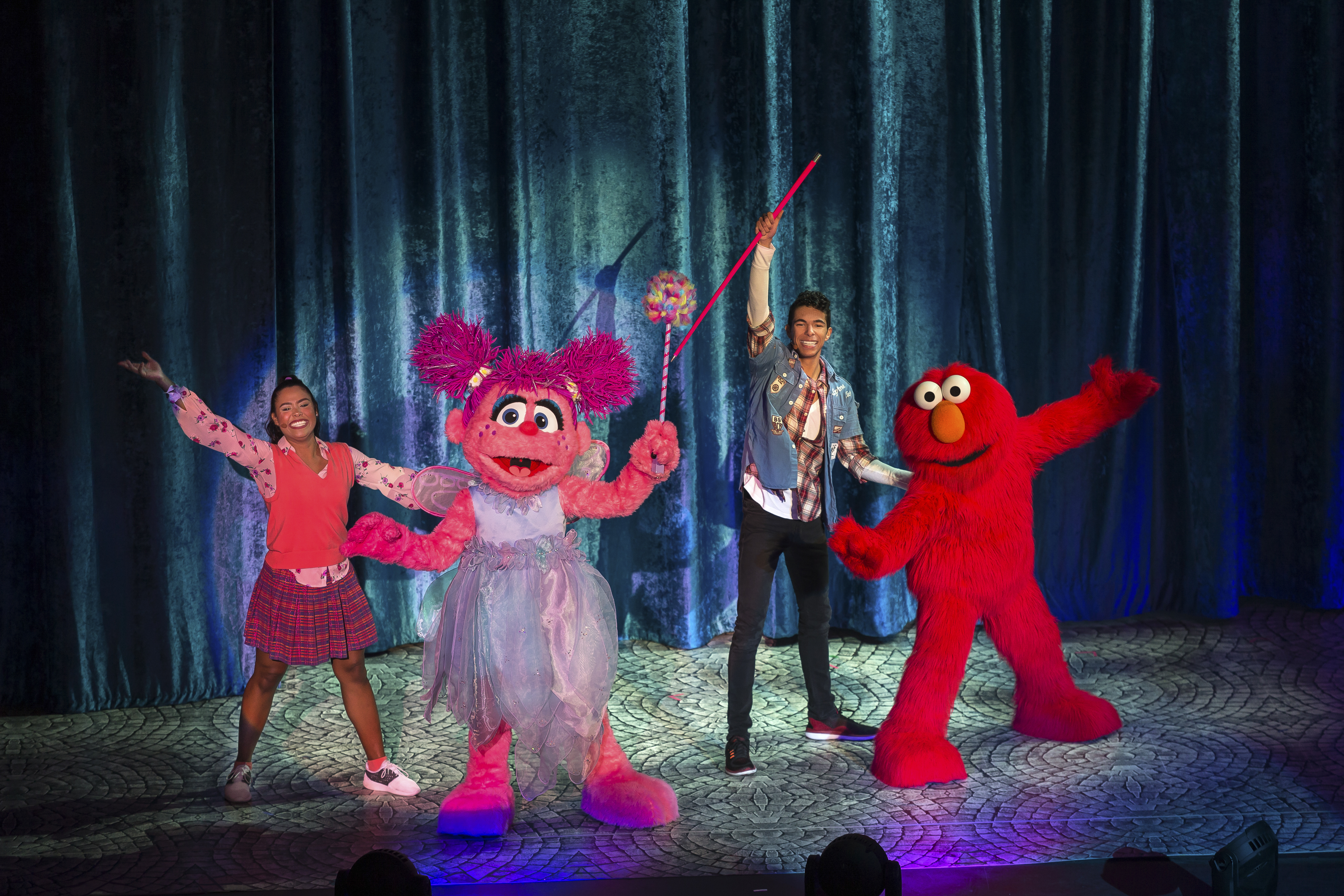 Sesame Street Live! characters dancing on stage.