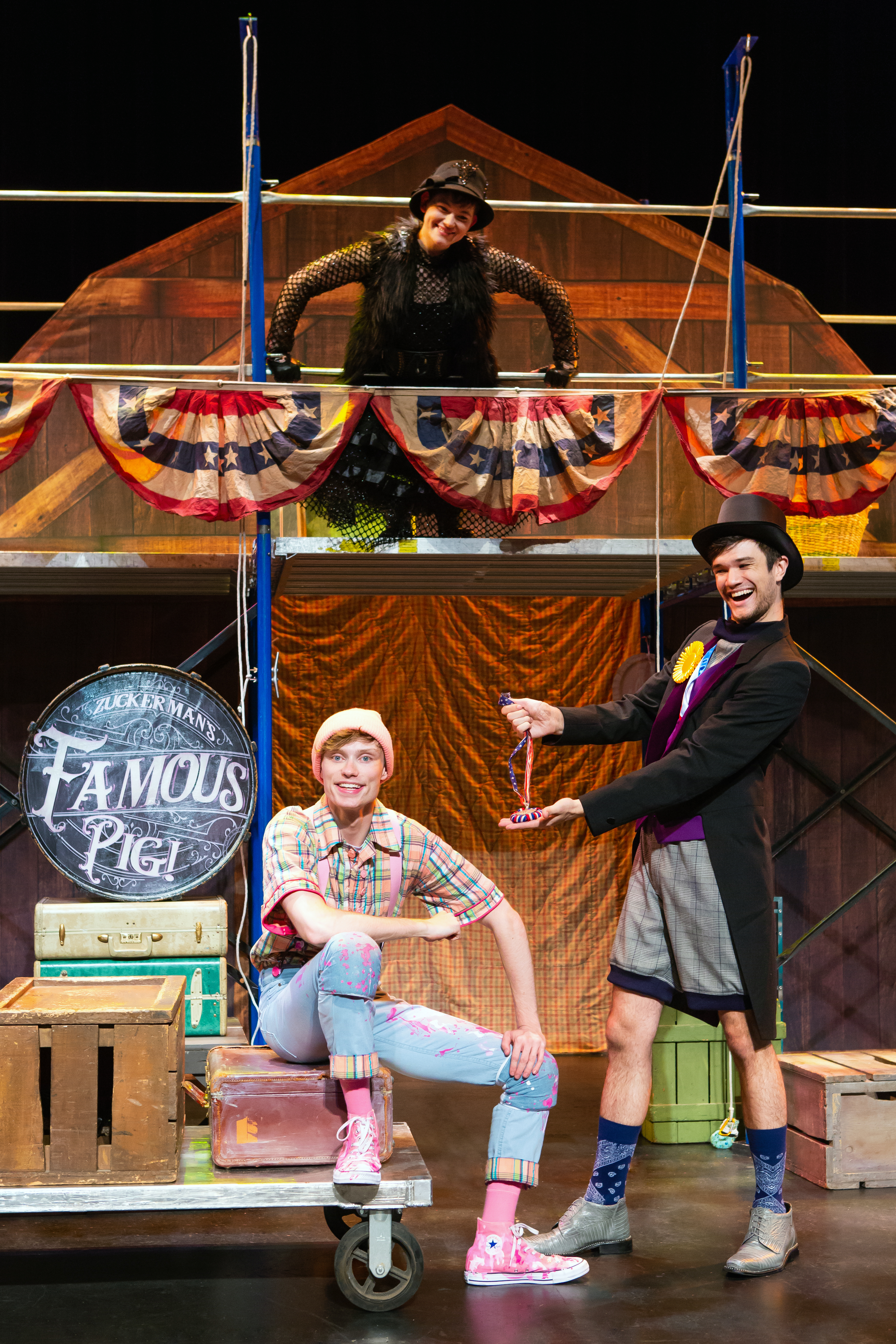 A man dressed as Wilbur the pig sitting beside a man hold up a prize ribbon. 