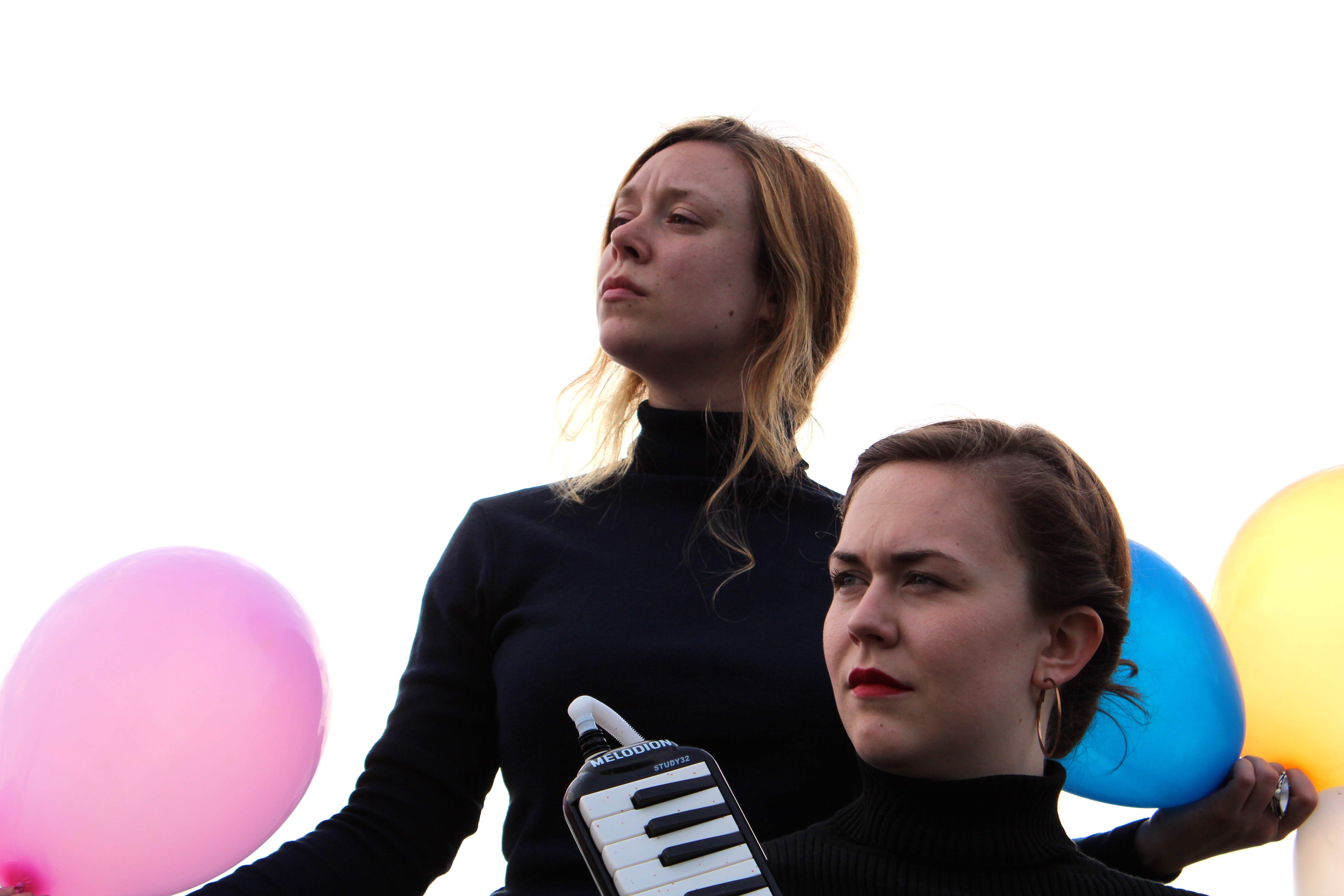 two ladies dressed in all black look off to the left