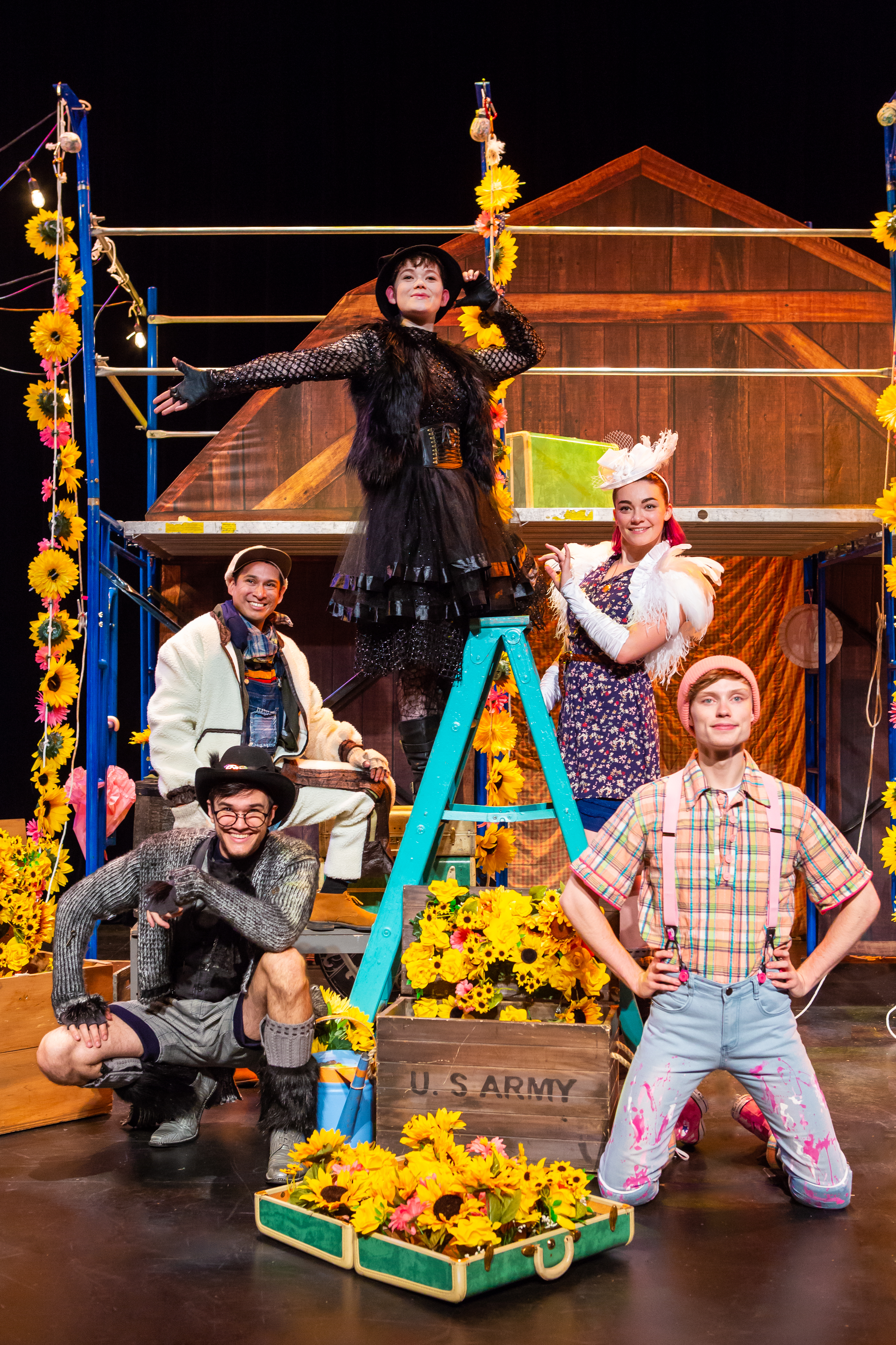 Five characters at various levels surrounding a blue ladder, there are also boxes of yellow flowers