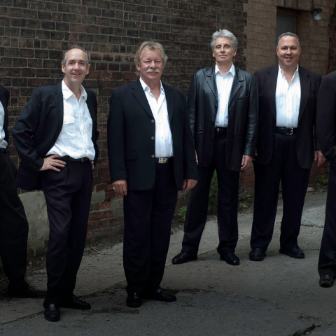 Four members of the band standing in suits. 