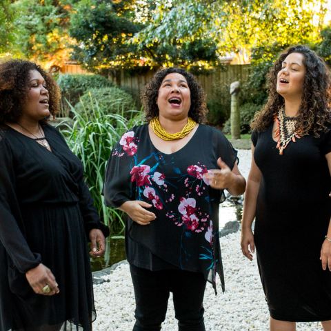 Four women singing outside. 