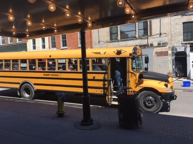 A school bus parked in front of Kingston Grand Theatre marquee