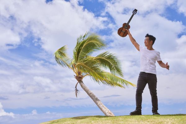 Man on a beach holding a ukelee