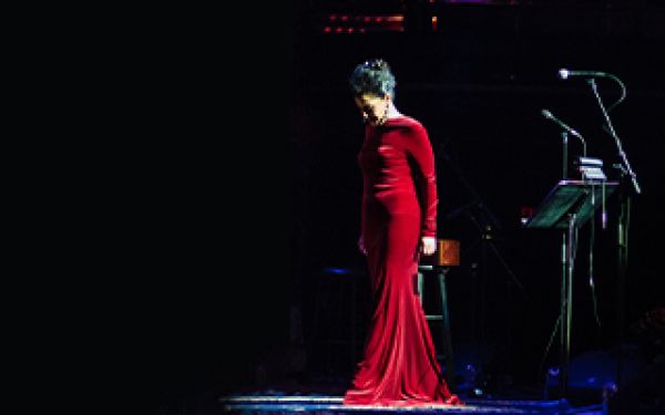 Molly Johnson in a long red dress, center stage