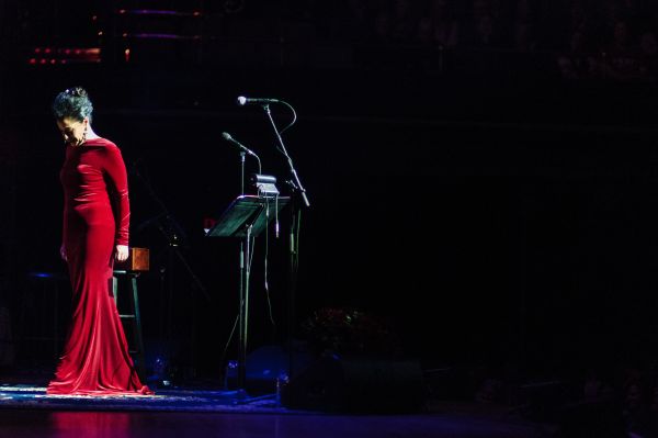 Molly Johnson in a red dress on stage, looking down and to the left.