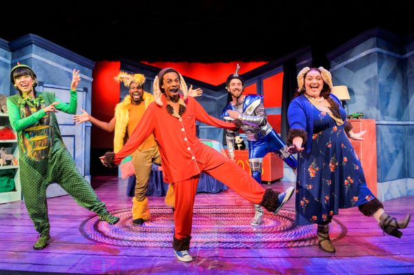 Five people dancing on stage dressed as characters from the book in colourful costumes