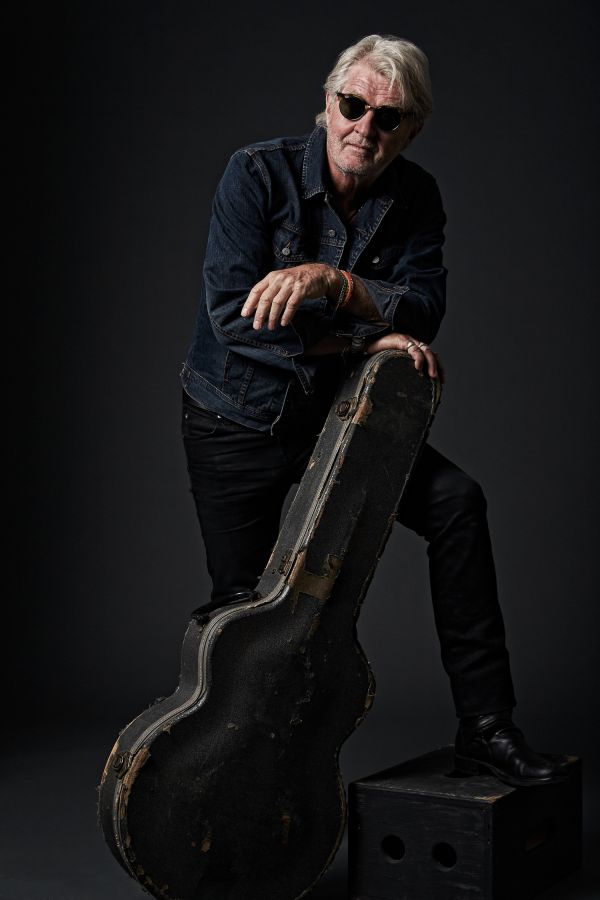 Tom Cochrane Portrait leaning on guitar case